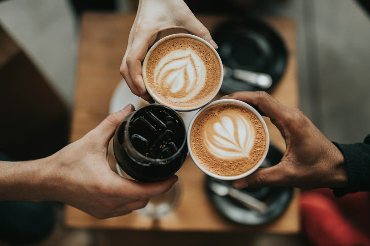 Tre persone brindano con un caffè al tavolino di un bar